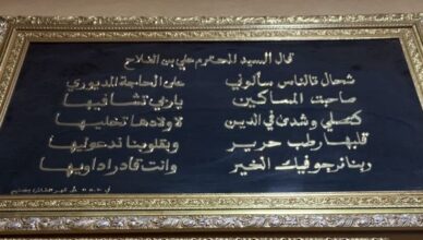 una targa incorniciata in stile dorato con un testo scritto in caratteri arabi su uno sfondo nero. Il testo è una poesia in Darija